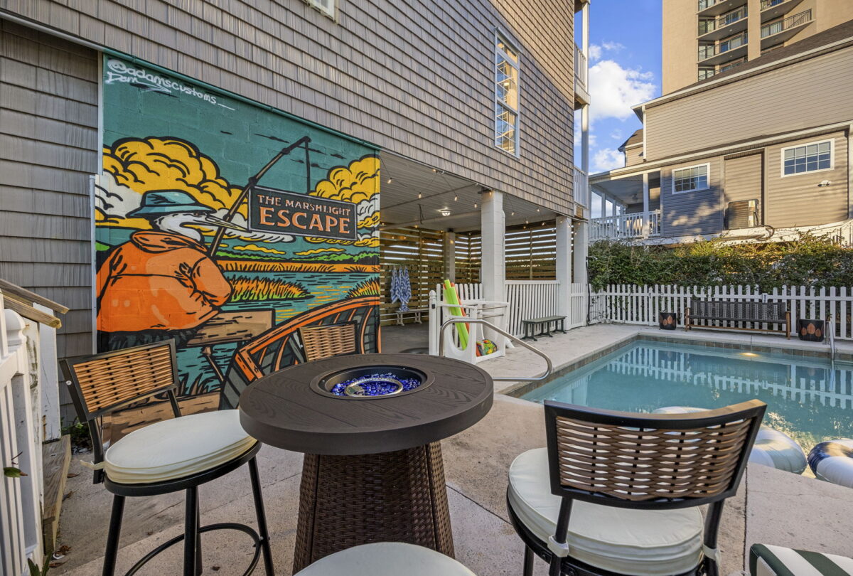 Poolside terrace with a fire table and a painted mural wall