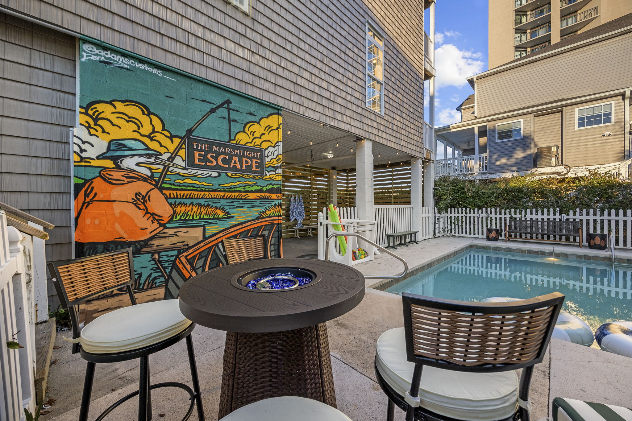 Poolside terrace with a fire table and a painted mural wall
