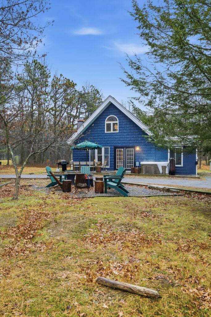 Blue cottage with a fire pit and Adirondack chairs in the garden