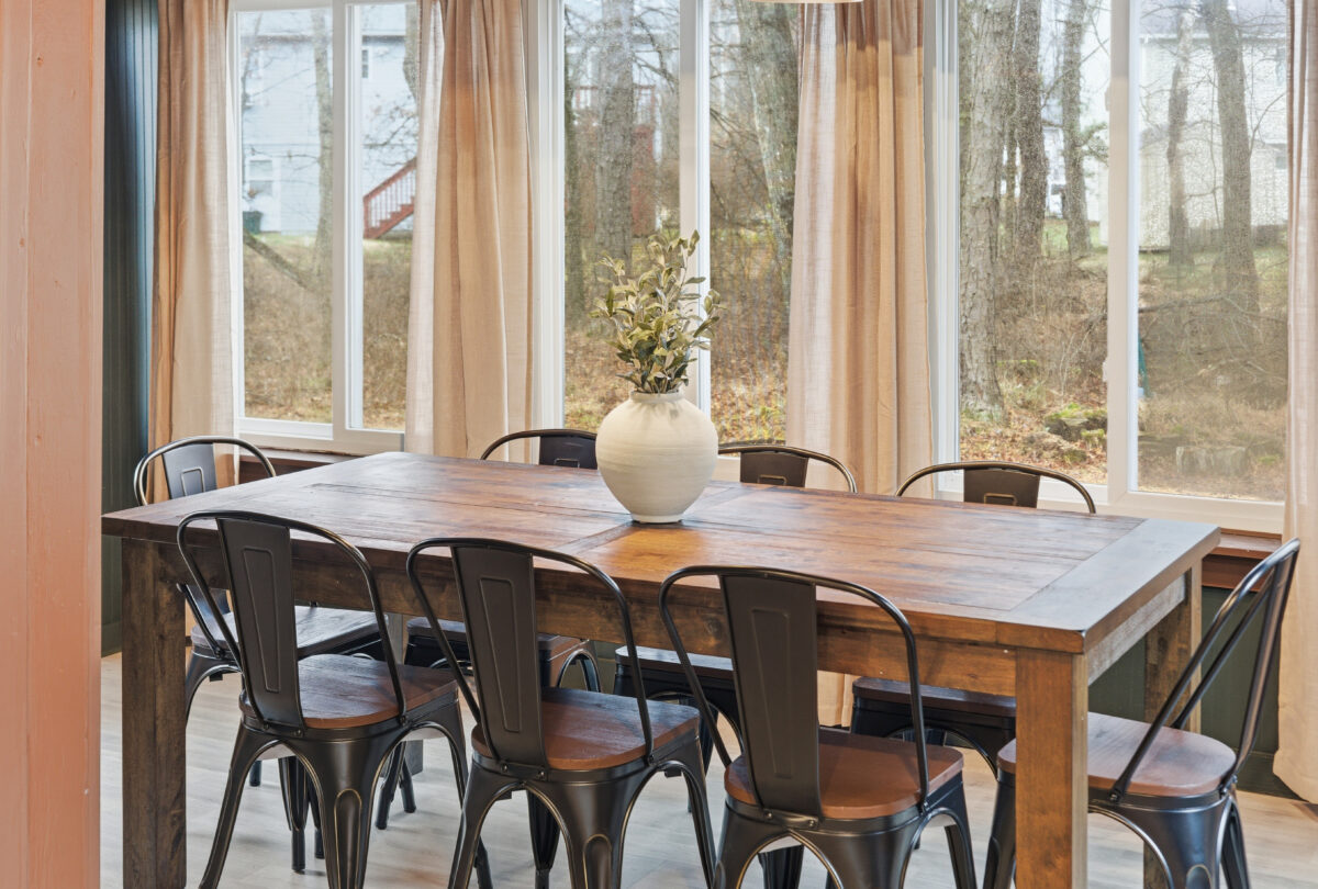 Dining room with a timber table and metal chairs beside tall windows