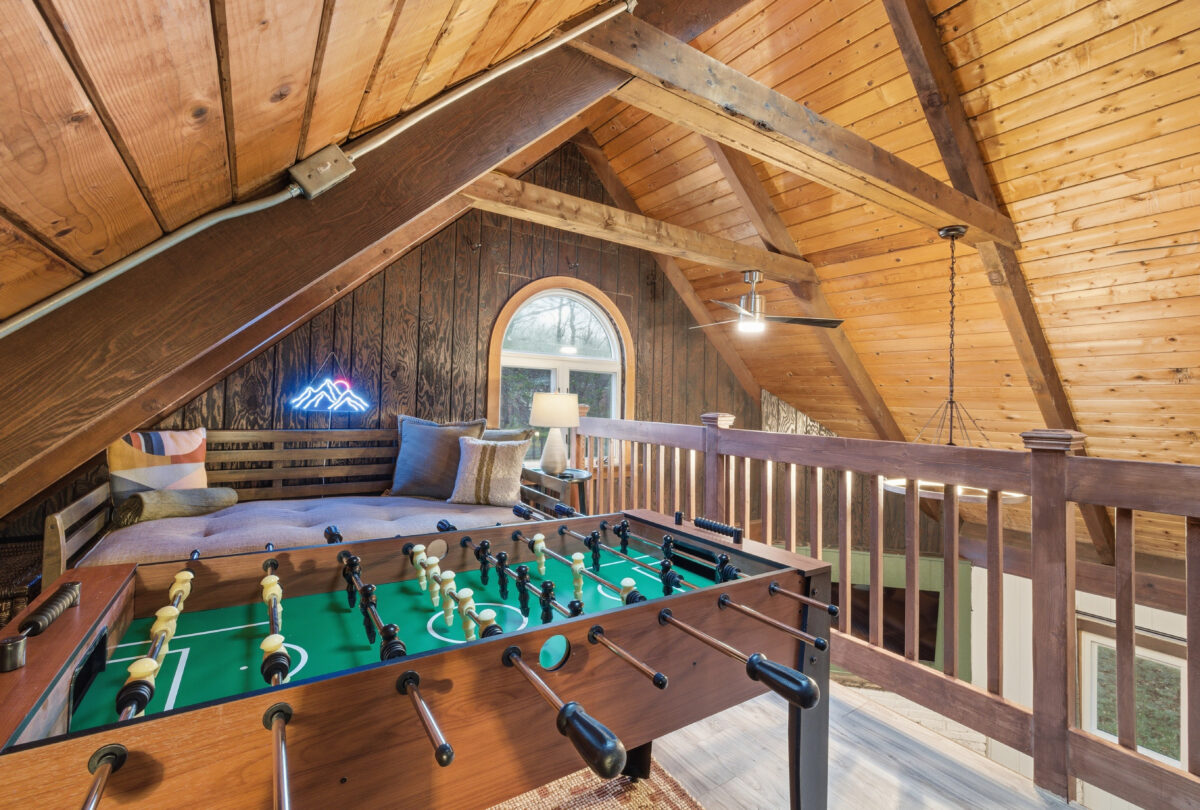 Attic games room with a foosball table under exposed timber beams