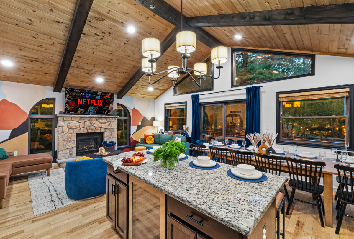 Open-plan kitchen island set for dinner beside a stone fireplace