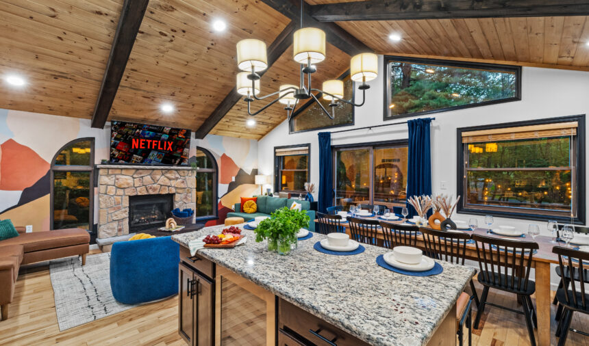Open-plan kitchen island set for dinner beside a stone fireplace