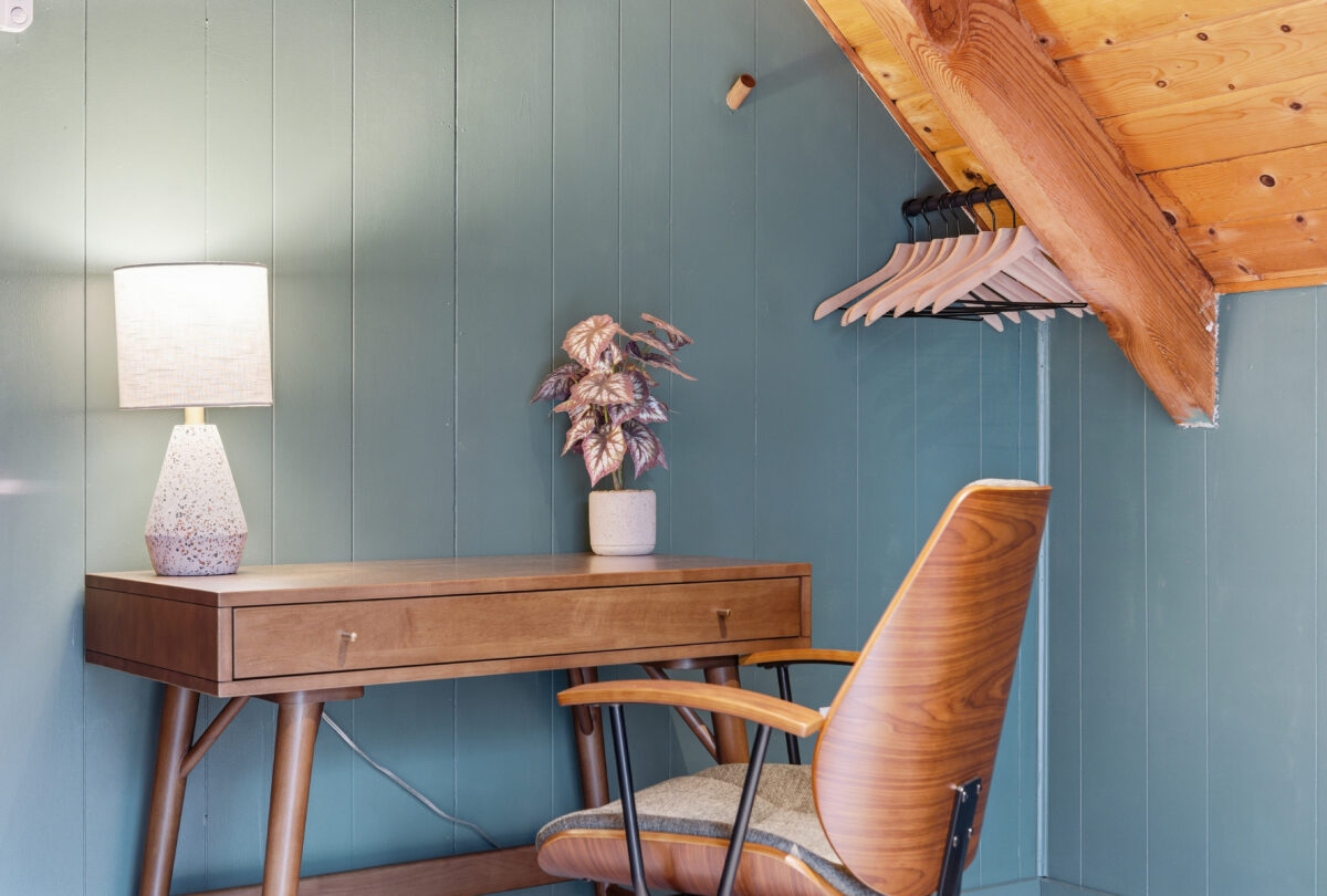 Desk with a leather chair against sage panelling under a timber ceiling
