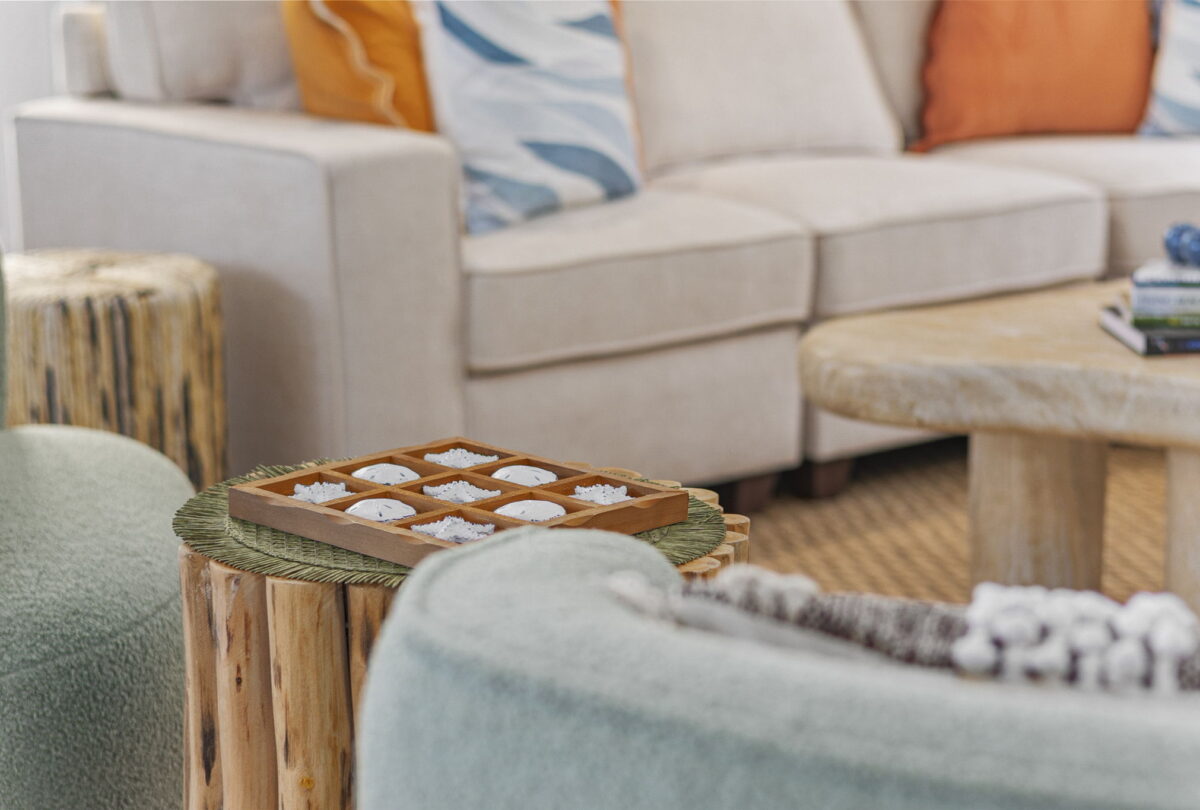 Noughts and crosses set on a timber side table beside a cream sofa