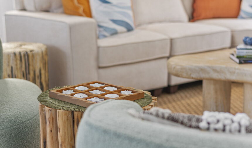 Noughts and crosses set on a timber side table beside a cream sofa