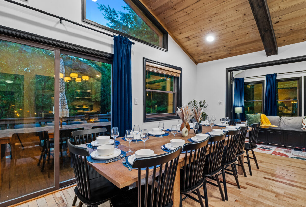 Long dining table set for twelve beneath a timber vaulted ceiling