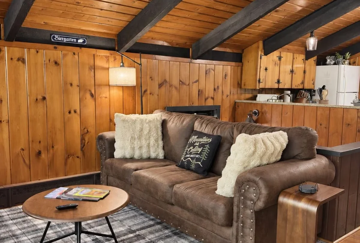 Living room with a leather sofa and plaid rug under exposed beams