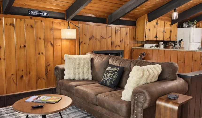 Living room with a leather sofa and plaid rug under exposed beams