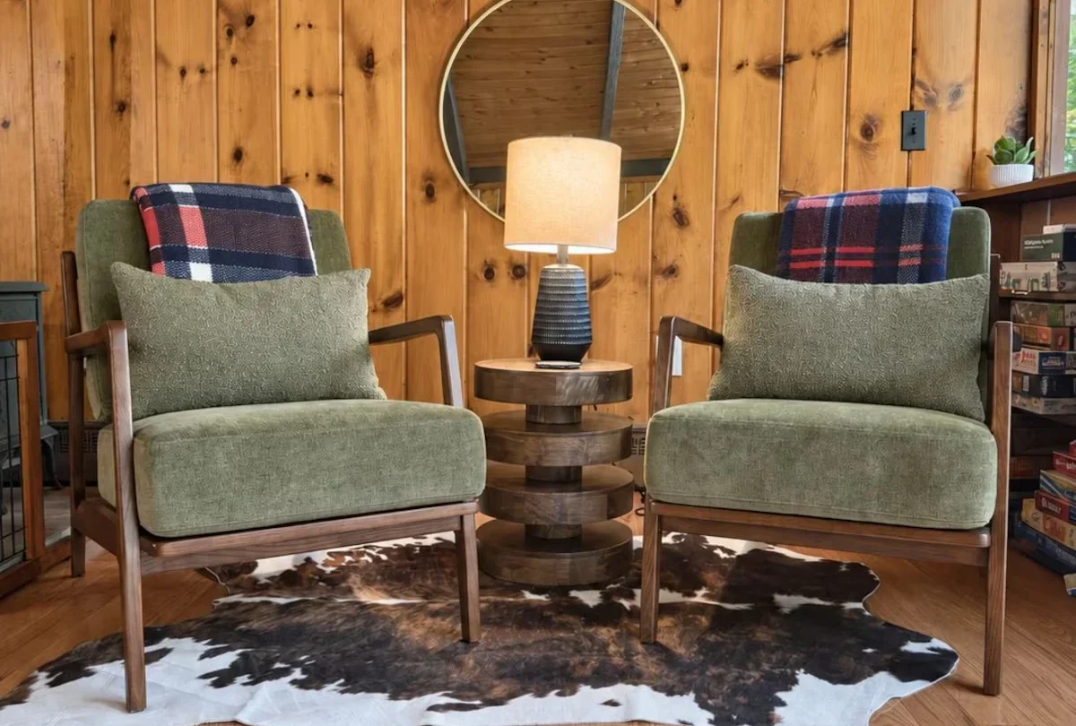 Two green armchairs beside a bookshelf in the knotty pine living room
