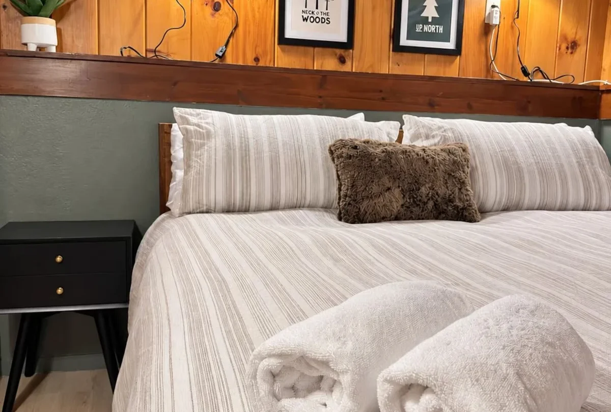 Bedroom with rolled towels on the bed and a sage green wall
