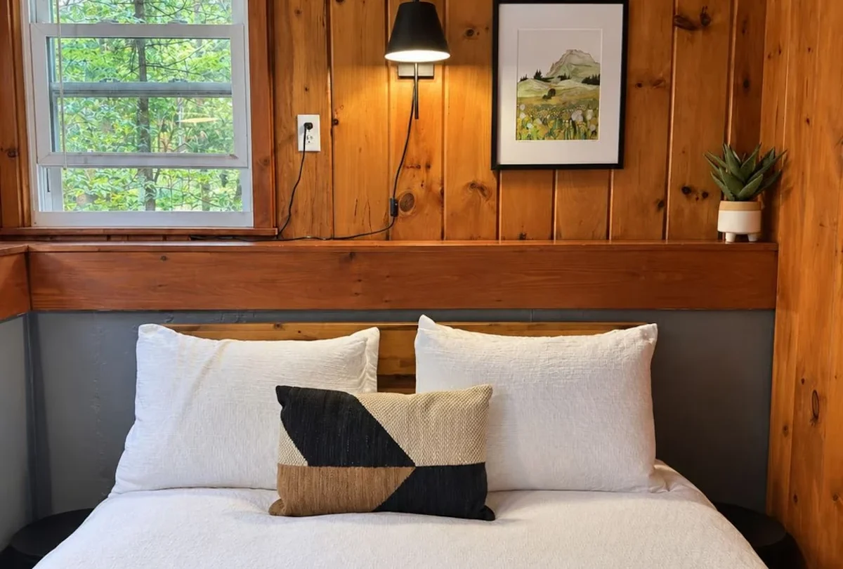 Bedroom with a framed print above the bed and pine walls
