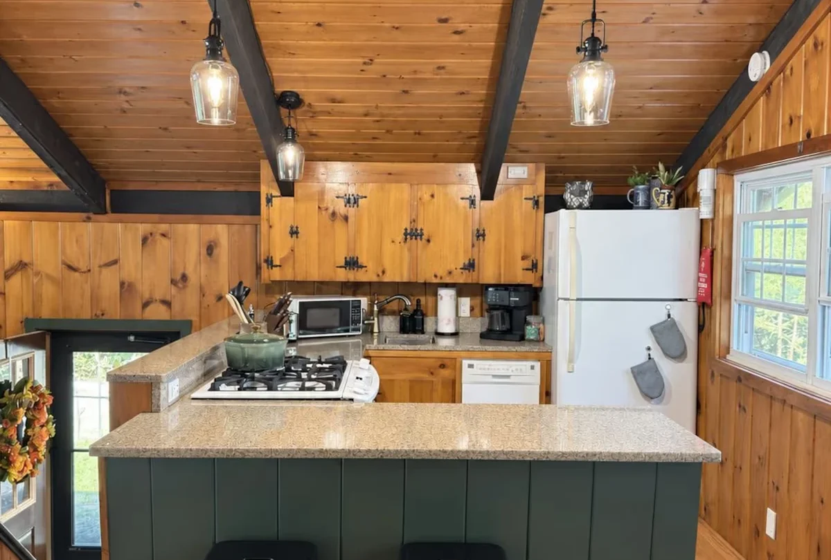 Kitchen with a green island and bar stools