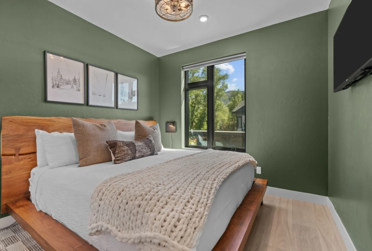 Bedroom with green walls and framed prints