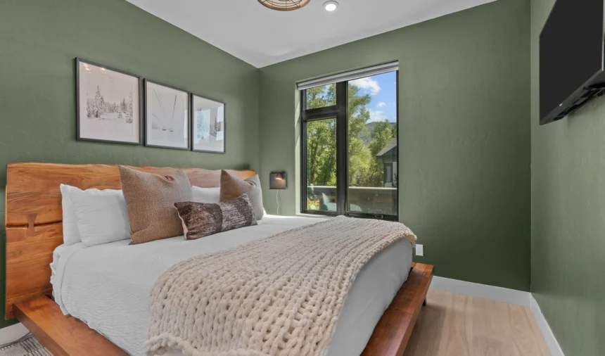 Bedroom with green walls and framed prints