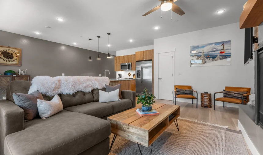 Living room with a grey sofa, timber table and plaid wallpaper