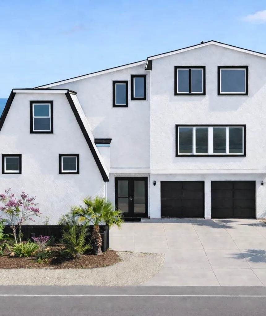 White oceanfront house with black-framed windows and palm trees