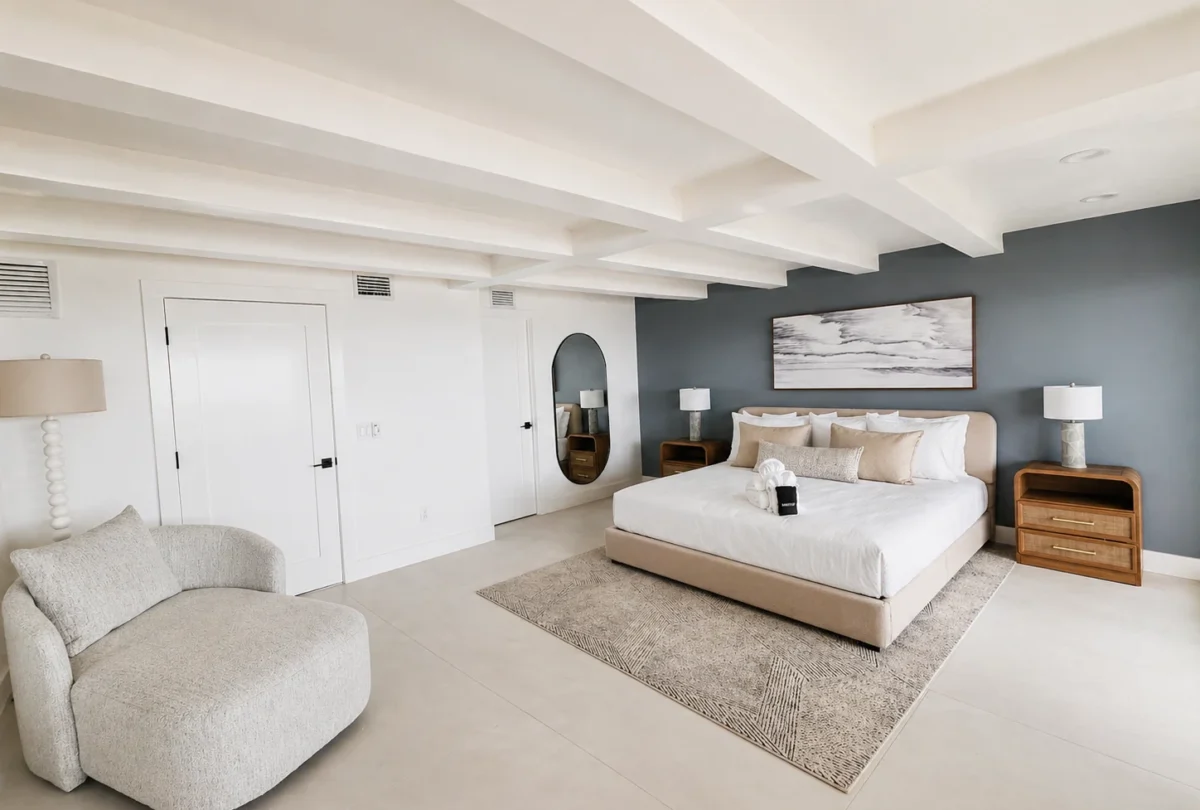 Primary suite with a coffered ceiling and a bouclé armchair