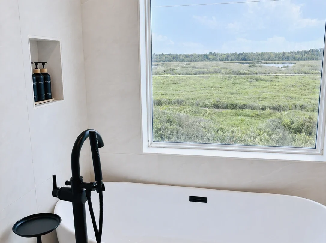 Freestanding bath facing a window onto the dunes