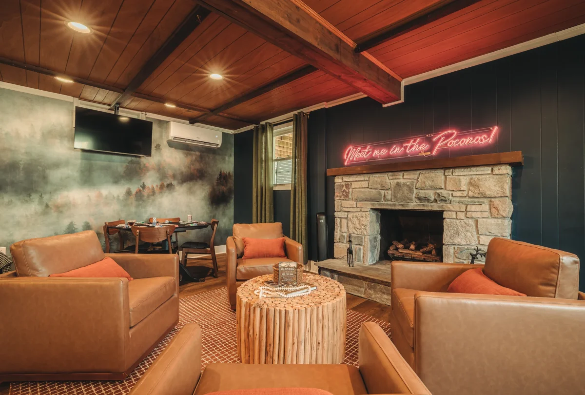 Lounge with a stone fireplace below a neon sign reading Meet me in the Poconos