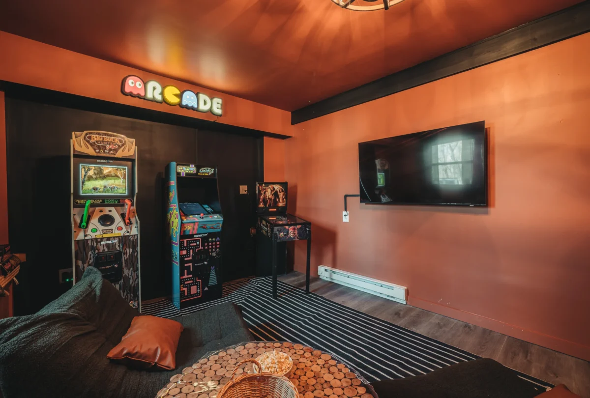 Games room with arcade cabinets and a neon arcade sign