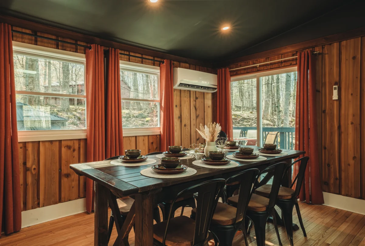 Long dining table set beside windows onto the woods