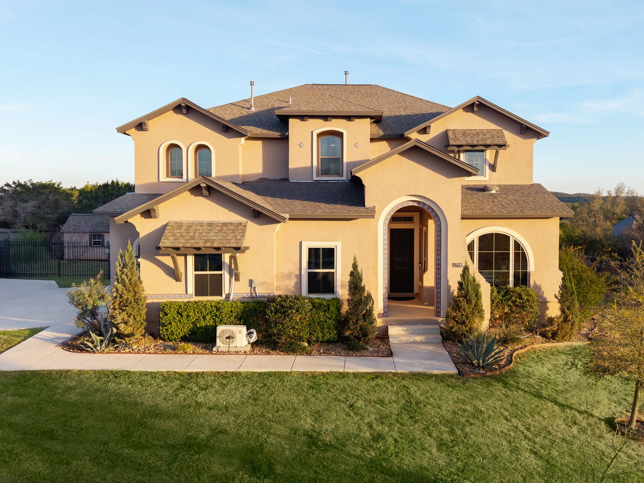 Stucco house with a tile roof seen from the front lawn