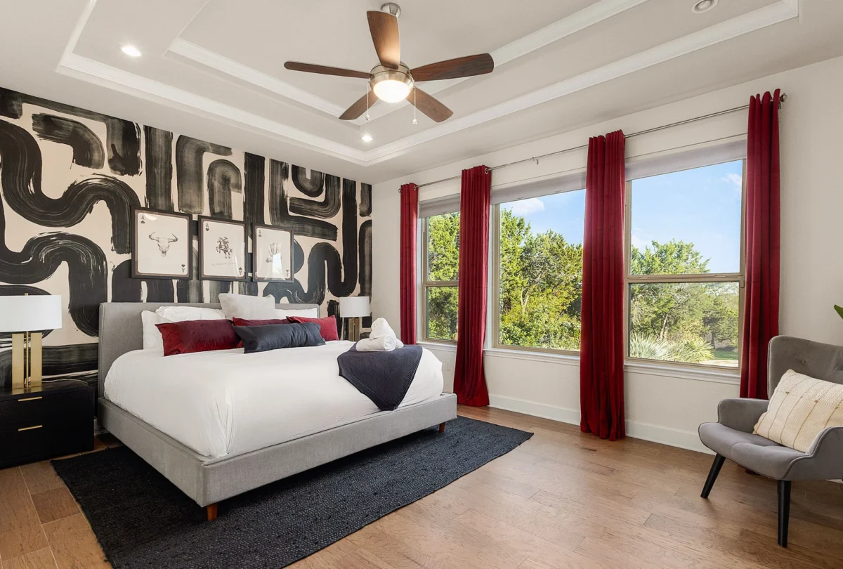Primary bedroom with a patterned feature wall and red curtains