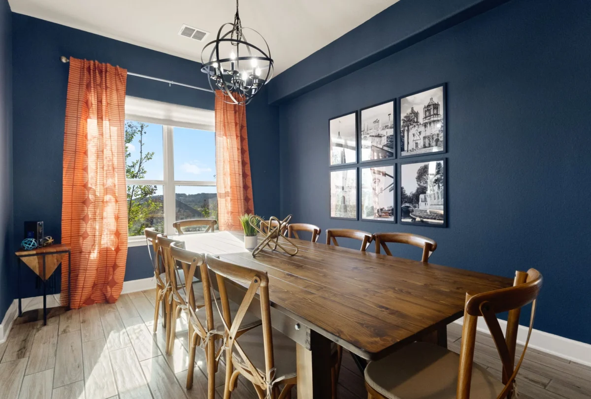 Dining table beneath an iron chandelier against a navy wall