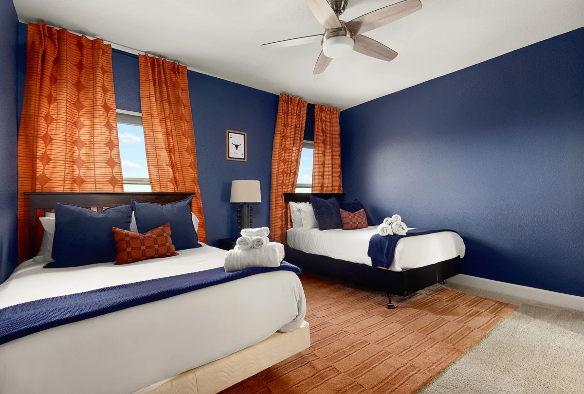 Bedroom with two beds, a navy wall and orange curtains
