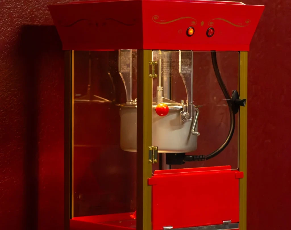 Red popcorn machine beside the cinema room poster