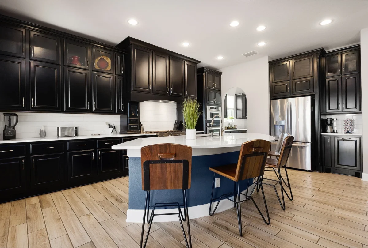 Kitchen with dark cabinetry and a long island with stools