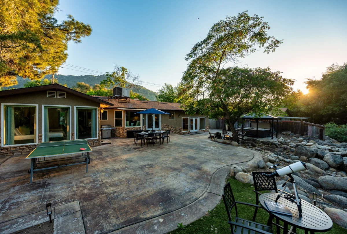The house lit at dusk, seen from the stone patio