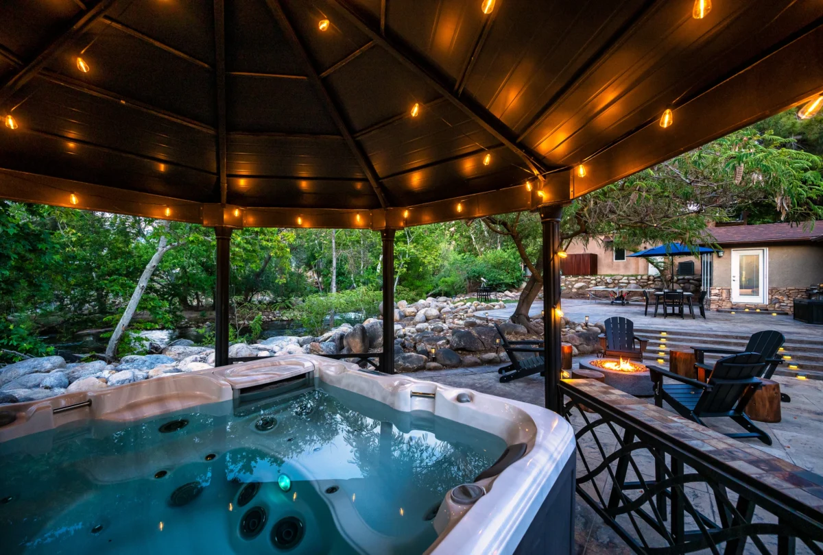 Hot tub under a pergola strung with lights at dusk