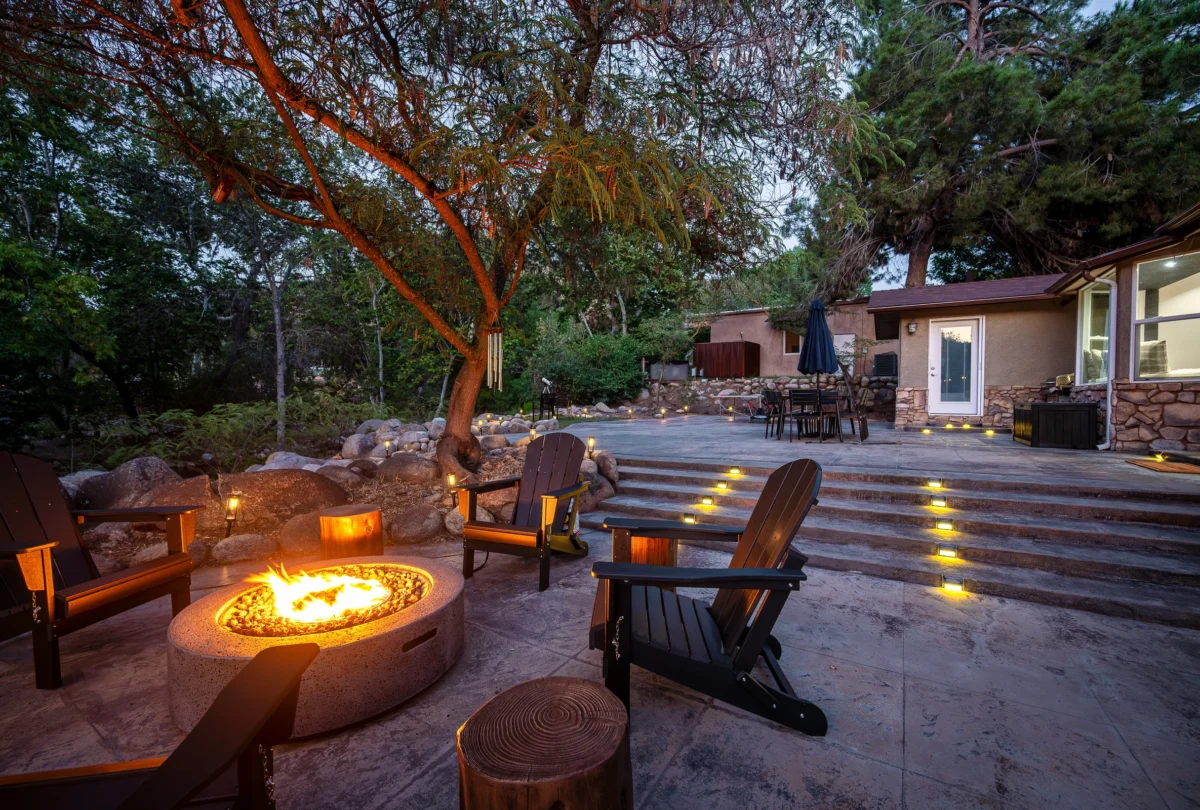 Lit fire pit ringed by Adirondack chairs at dusk