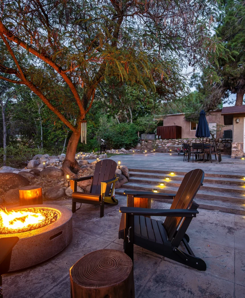 Lit fire pit ringed by Adirondack chairs at dusk