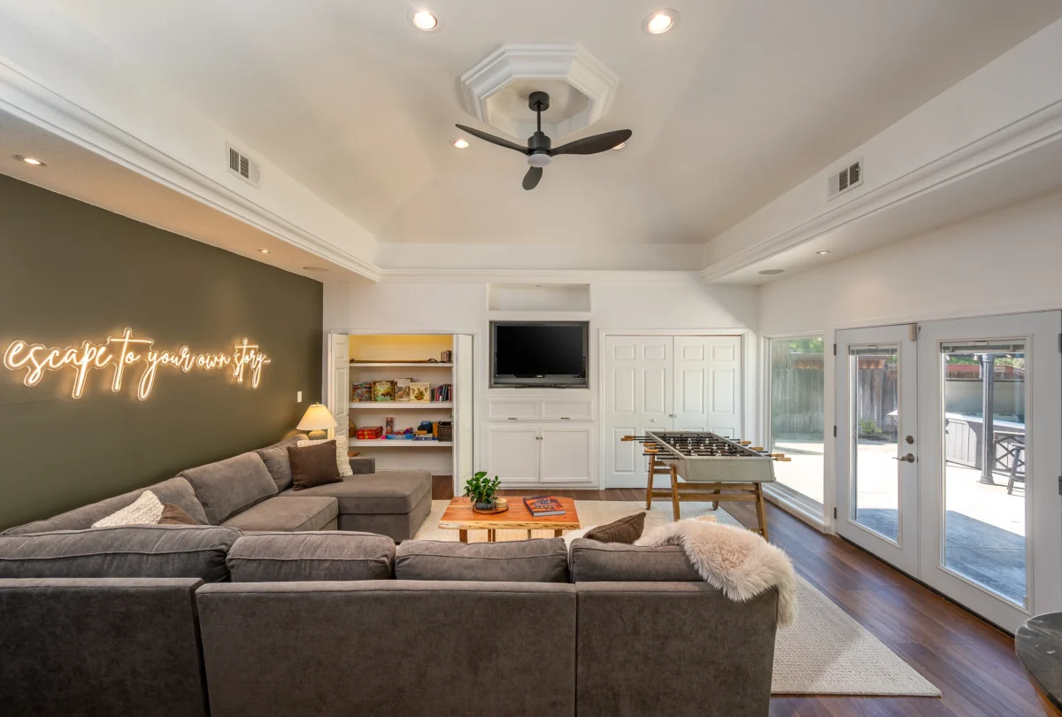 Lounge with a sectional sofa, foosball table and a neon sign reading escape to your own story
