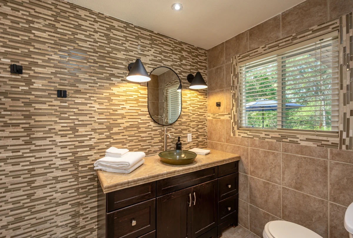 Bathroom with a stacked stone wall and a round mirror