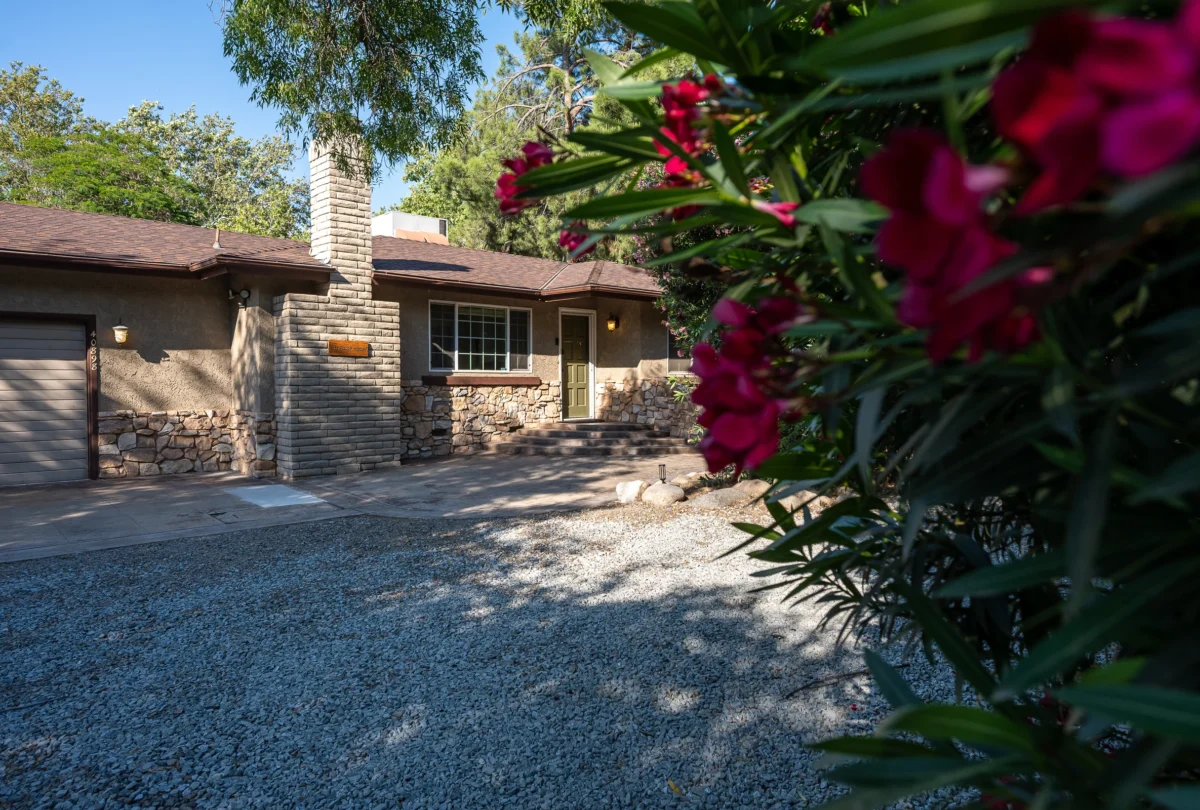 Stone exterior of The Fable House behind a flowering shrub