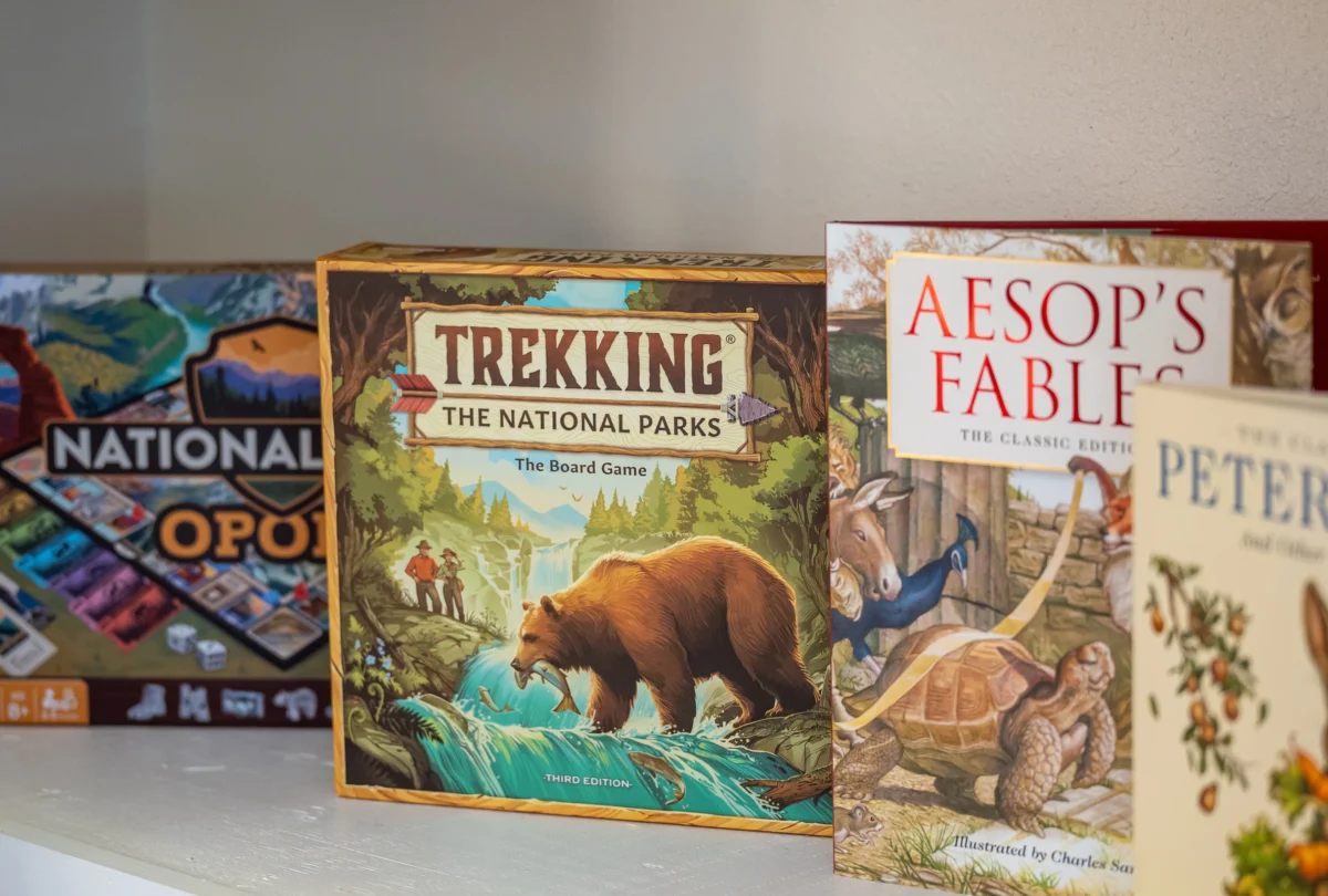 Board games stacked on a shelf, including Aesop's Fables