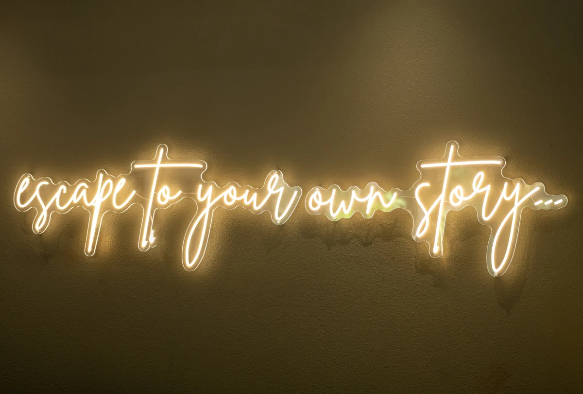 Neon script sign reading escape to your own story