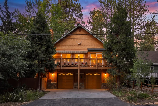 The cabin lit among the pines at dusk