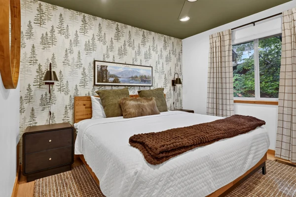 Bedroom with pine-tree wallpaper and a brown throw
