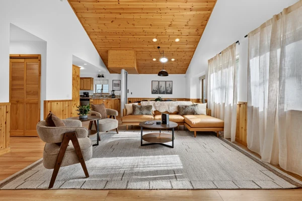 Living room under a pitched timber ceiling with sheer curtains