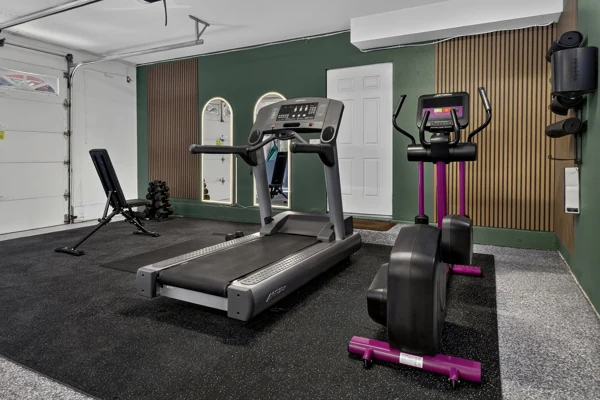 Home gym with a treadmill and cross trainer on rubber flooring