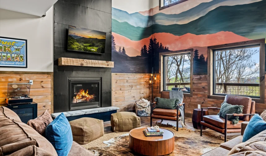 Living room with a lit fireplace below a layered mountain mural