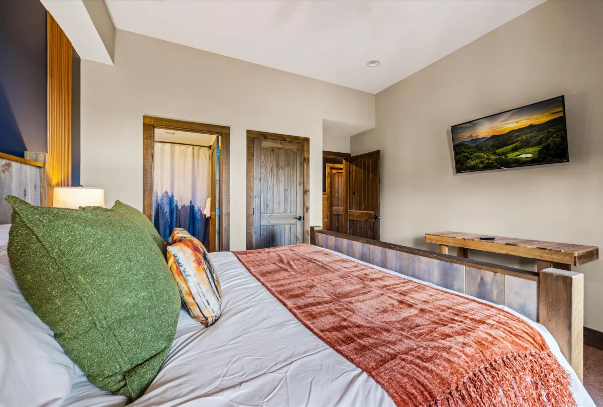 Bedroom with a forest print above the bed and a rust throw