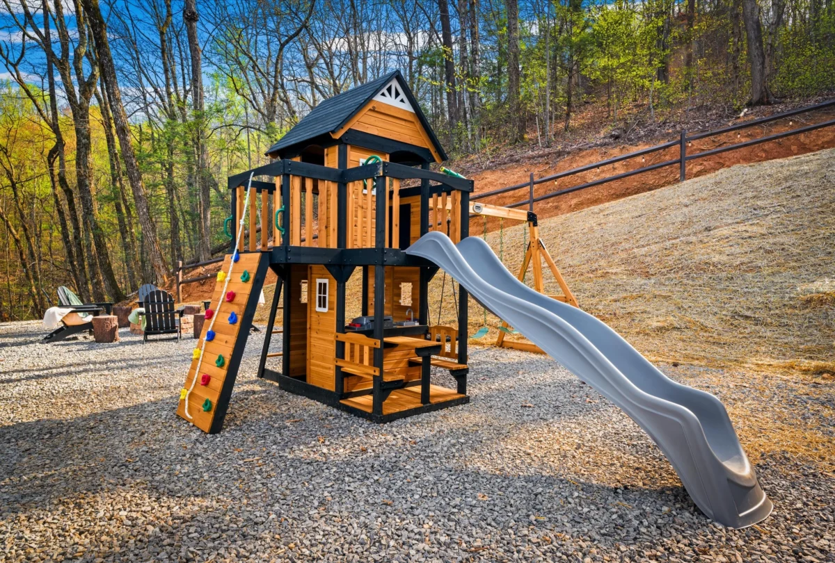 Timber play structure with a slide beside the cabin