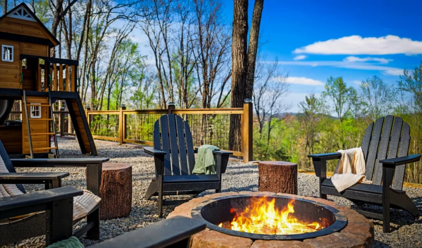 Lit fire pit ringed by Adirondack chairs among the trees