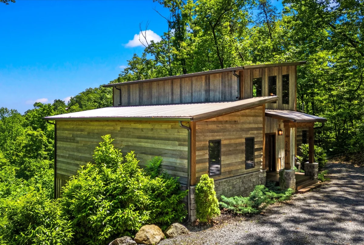 The cabin seen from the gravel drive between the trees